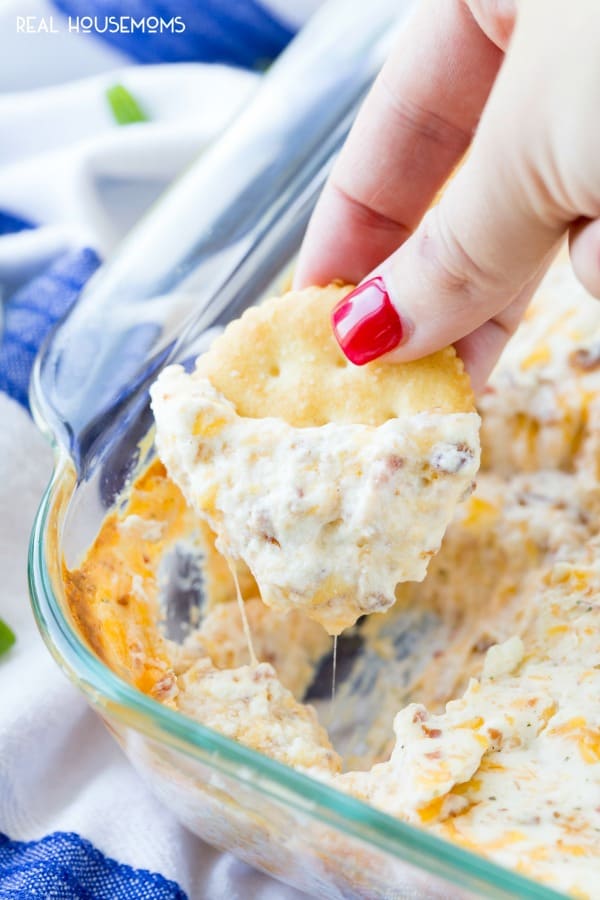 Cracker wird in eine Pfanne mit warmem Cheesy Crack Dip getaucht